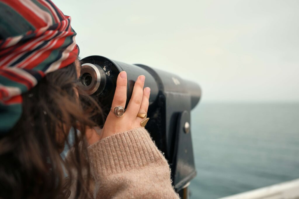 Woman looking at the telescope, showcasing adaptability skills of concern and curiosity to build a professional reputation and a long-lasting personal brand.