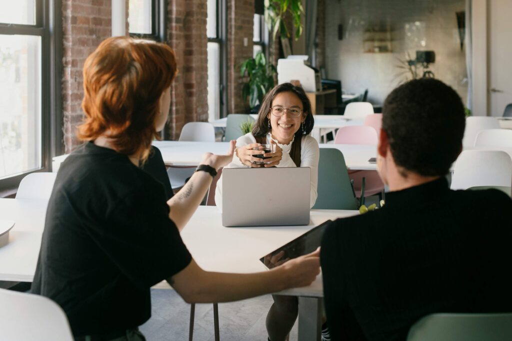 Diverse corporate professionals having a focused team discussion in a modern office workspace, with a laptop on the table, for a personal brand tips article