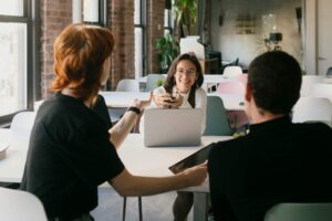 Diverse corporate professionals having a focused team discussion in a modern office workspace, with a laptop on the table, for a personal brand tips article